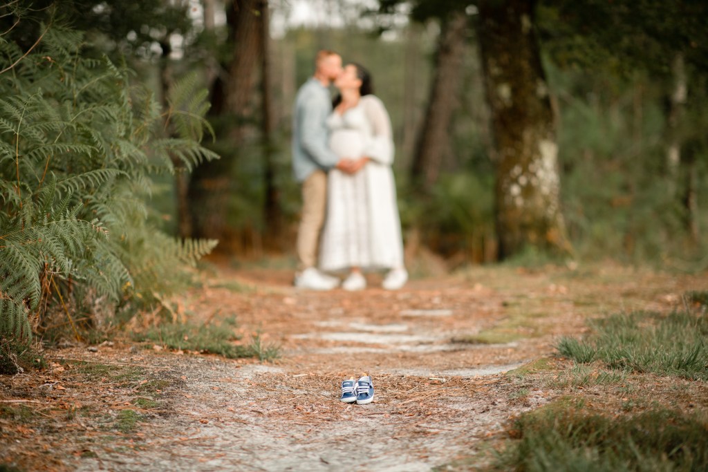 des chaussons de bébé au premier plan lors d'une séance photo grossesse à l'étang de sainte foy